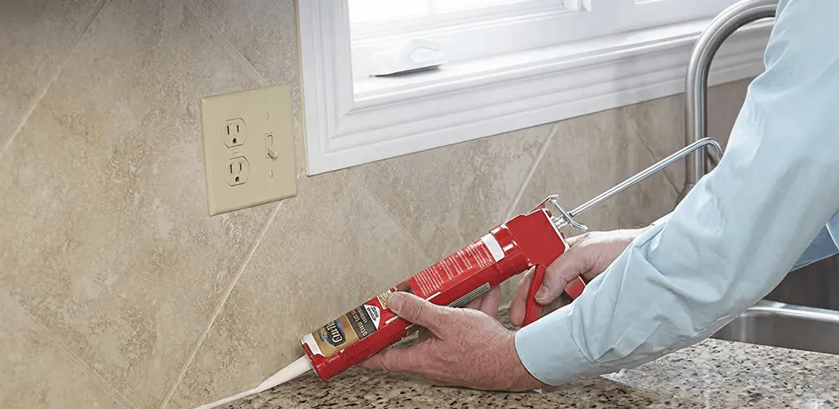 Handyman applying caulk along a kitchen backsplash and countertop seam in Memphis, TN