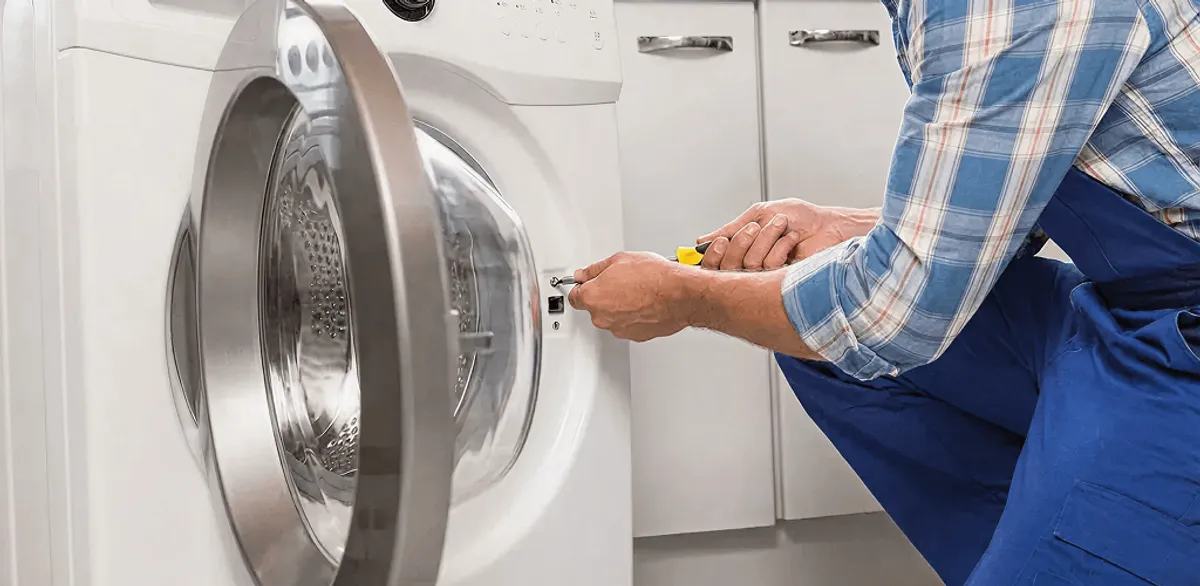 Handyman repairing a clothes dryer and checking electrical connections in Memphis, TN
