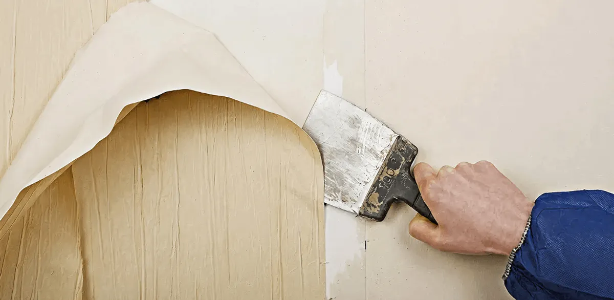 Handyman removing wallpaper with a scraper for wall preparation in Memphis, TN