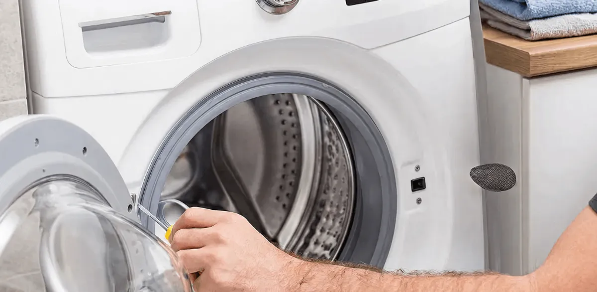 Handyman repairing a front-load washing machine and inspecting the drum in Memphis, TN