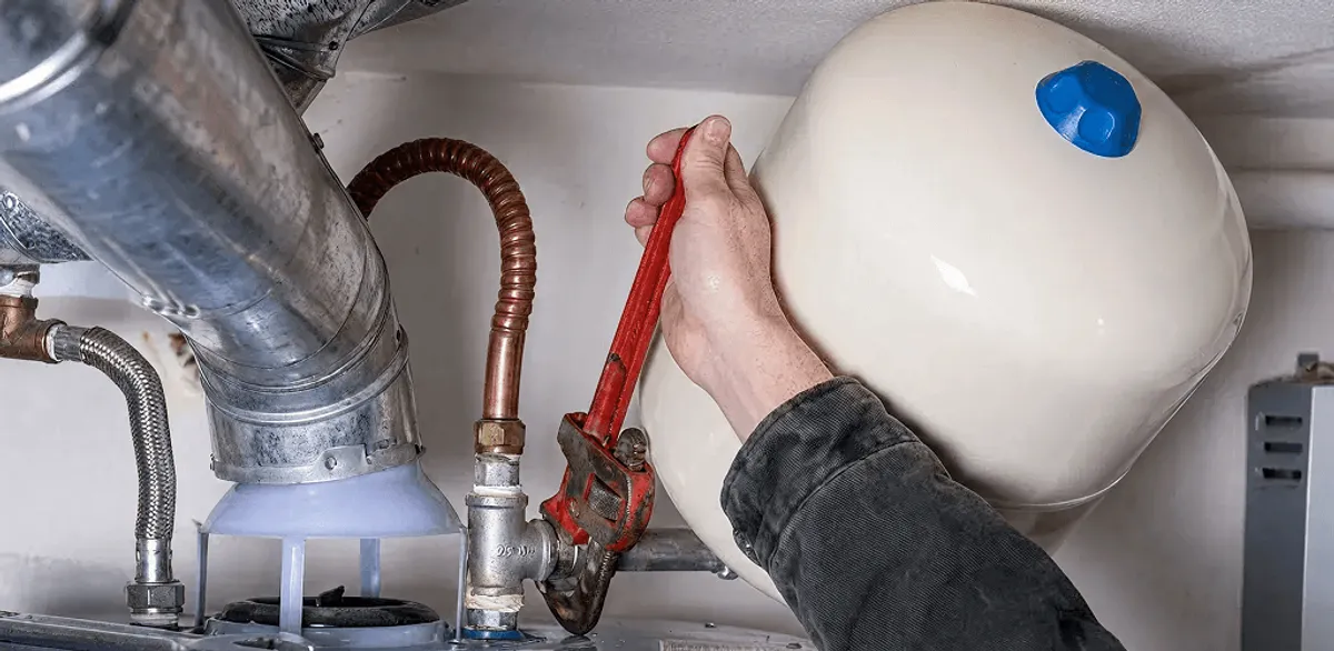 Water heater repair technician tightening plumbing connections near a tank unit in Memphis, TN